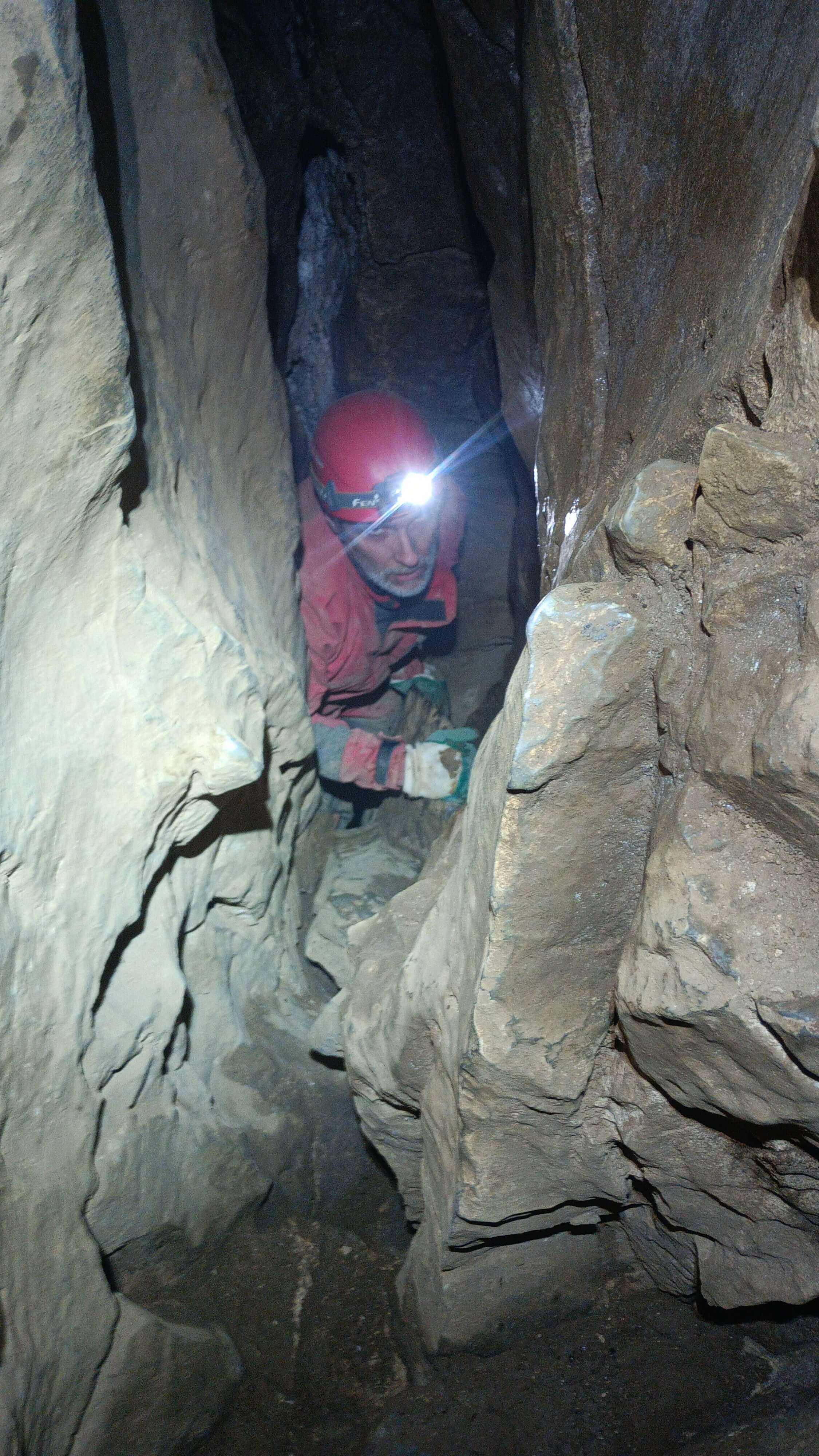 Pohled do tváře jeskyňáře zdolávajícího stoupající vstupní puklinu
